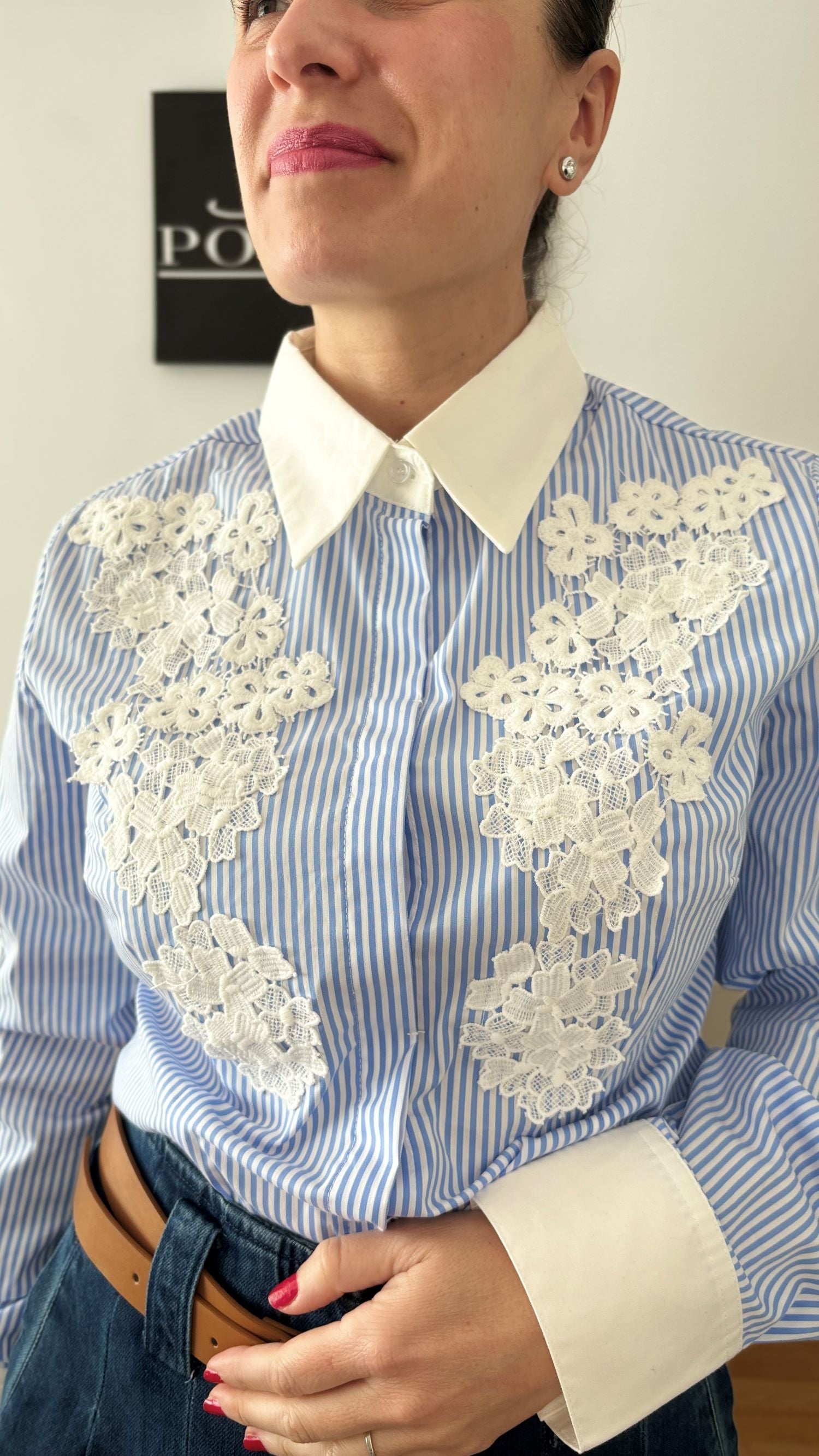 Mujer luciendo camisa de rayas azul y blanco con encaje floral, representando elegancia y estilo atemporal de PODENCO.